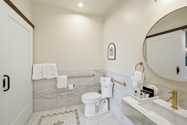Brightly lit wheelchair accessible bathroom, showing the vanity and toilet.