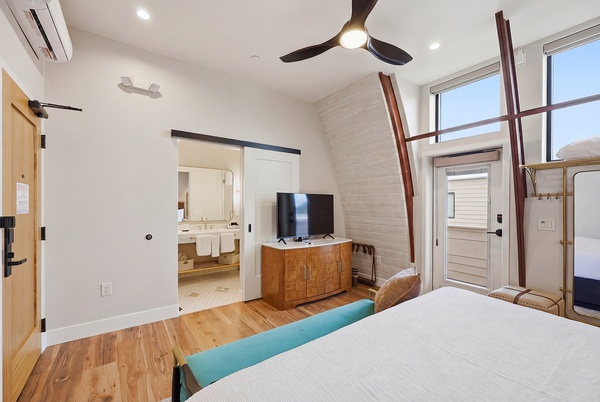 Deluxe 1 king bedroom showing the TV stand, white linens, and patio door.