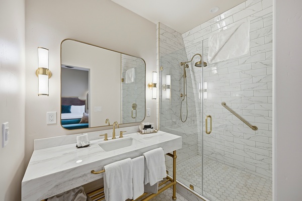 Deluxe 1 king bathroom showing vanity, overhanging shower, and white tile.